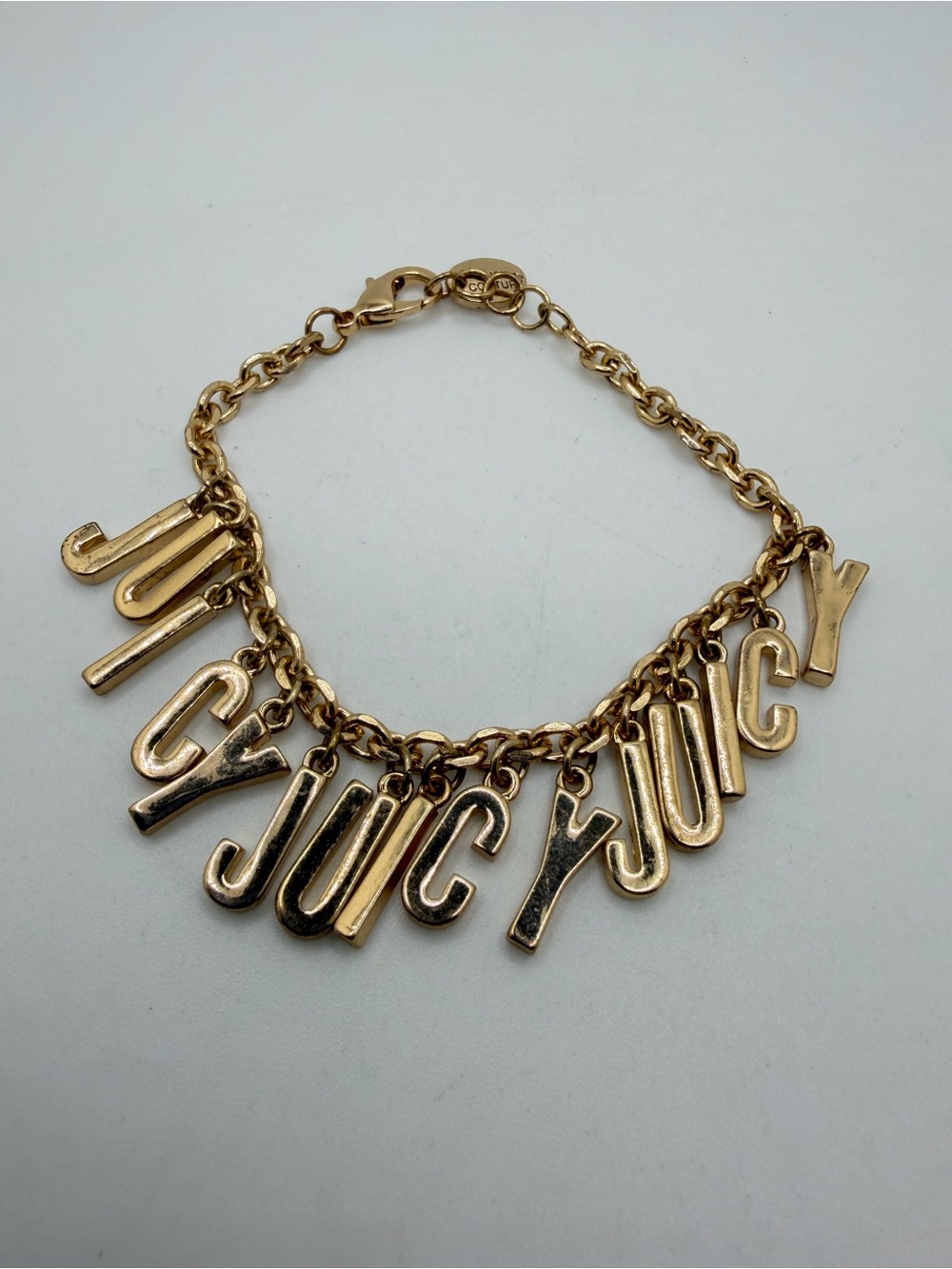 up to 7.5" Juicy Couture "Juicy Charm" bracelet in gold tone metal!